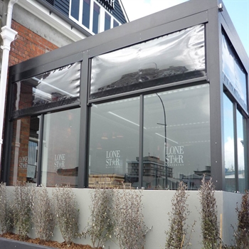 a restaurant patio enclosed with glass panels that are covered with clear pvc screens for protection
