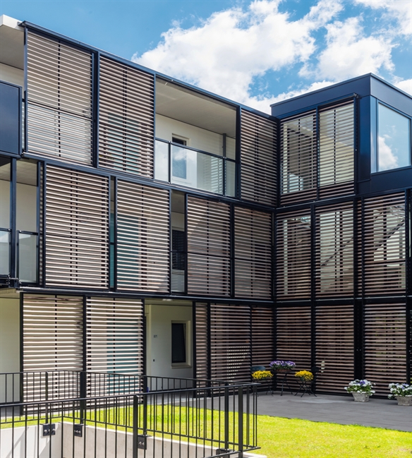 brown louvred aluminum sliding shutter panels installed outside of balcony railings of apartments