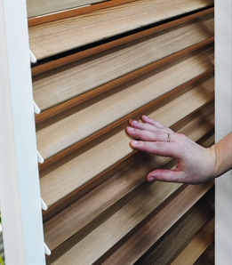 close up of sliding shutter panel with wooden style louvres being manually tilted by hand