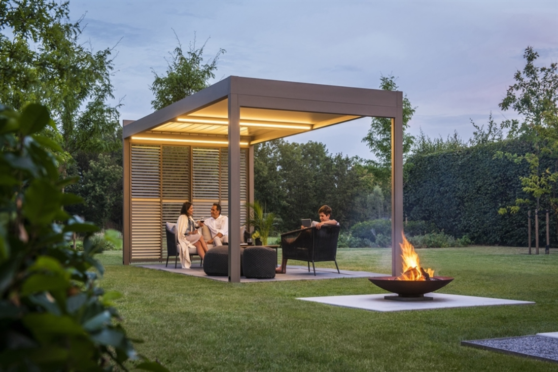 black louvred pergola with black louvres sitting in the garden surrounded by grass