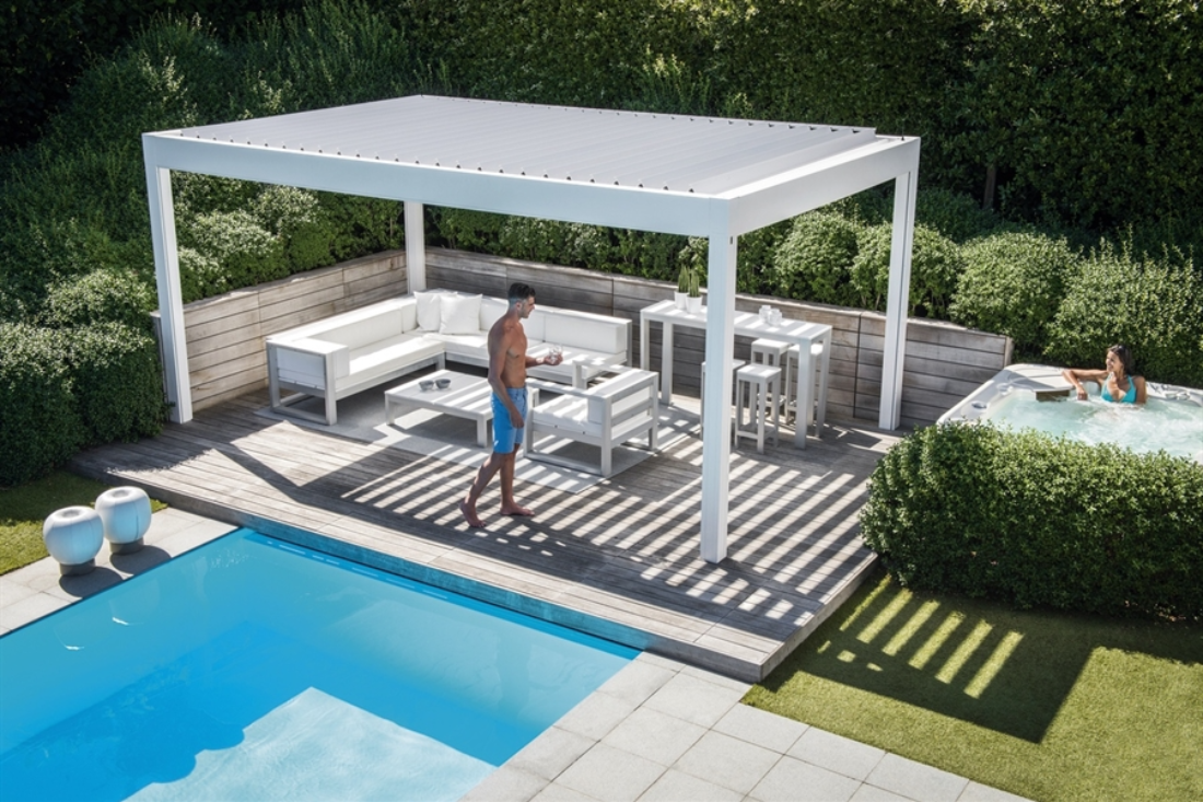 white louvred pergola in a backyard next to pool with people underneath