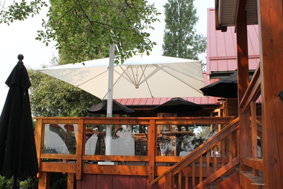 people seated in a curbside restaurant patio covered by red umbrellas above