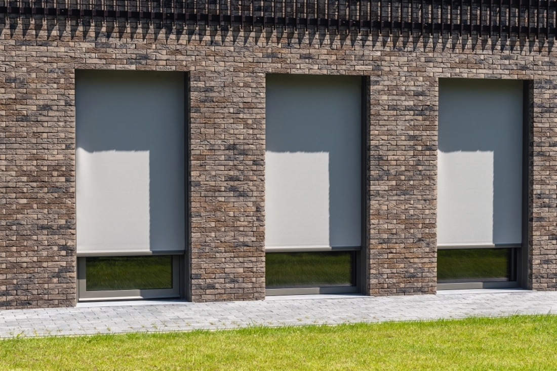 brick style building with windows that have grey external roller blinds covering windows