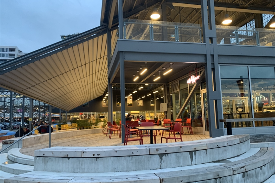 grey pvc fabric pergola installed above an ice rink mounted to a building