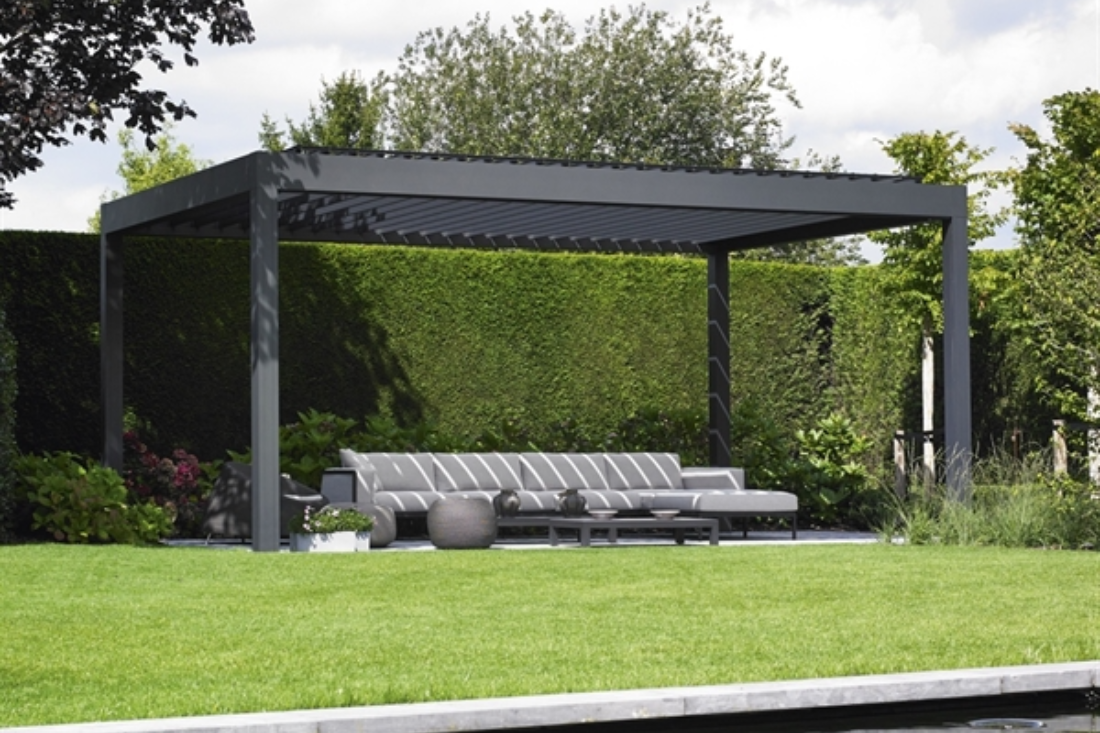 black louvred pergola with black louvres sitting in the garden surrounded by grass