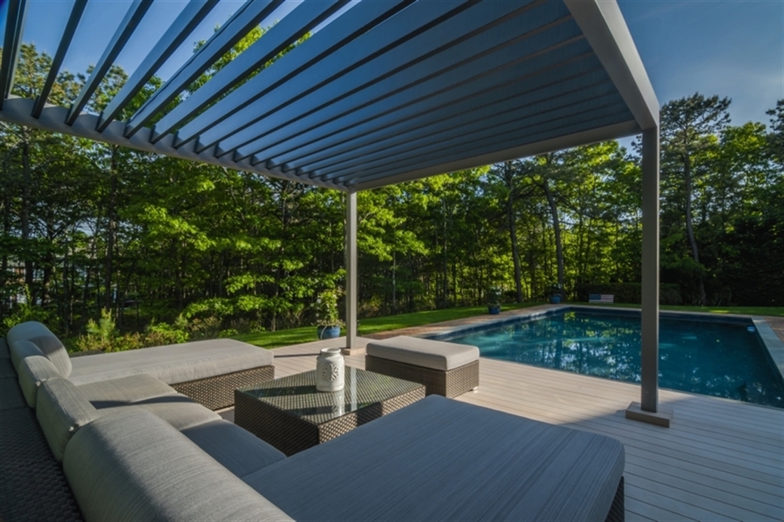 grey louvred bioclimatic pergolas attached to each other with lighting in a backyard