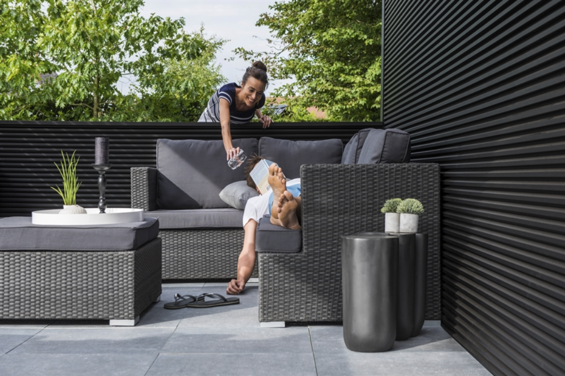 black louvred pergola with black louvres sitting in the garden surrounded by grass