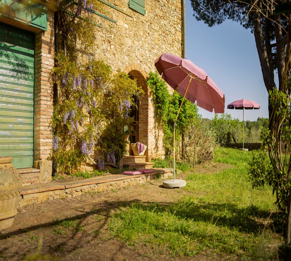 2 classic umbrellas in pink fabric in an open grass area of an establishment with circular bases