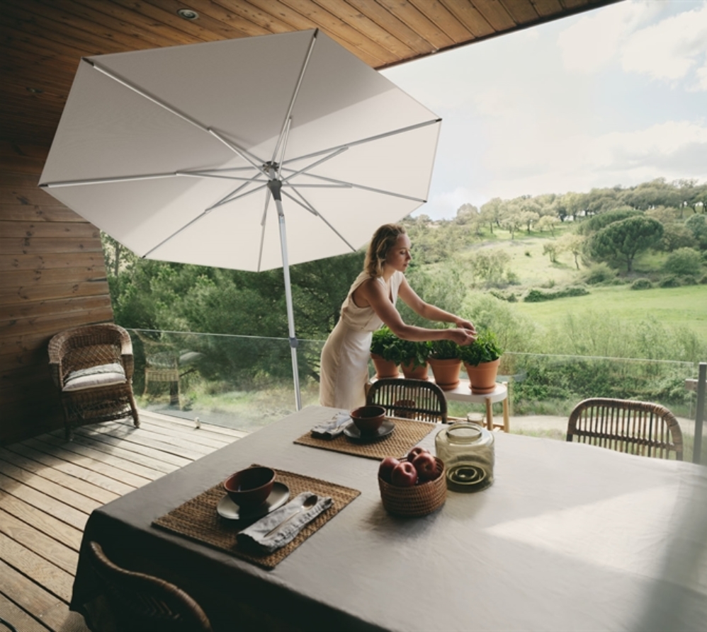 A small white umbrella on a second level deck shading a lady who is tending to her plants