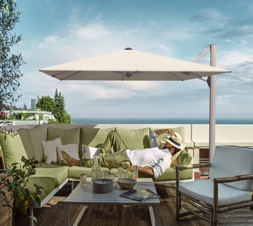 Gentleman sleeping on a green sofa underneath a white umbrella overlooking the ocean