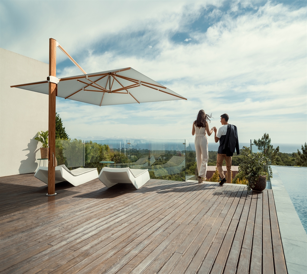 2 people holding hands on a patio overlooking many trees next to an infinity pool