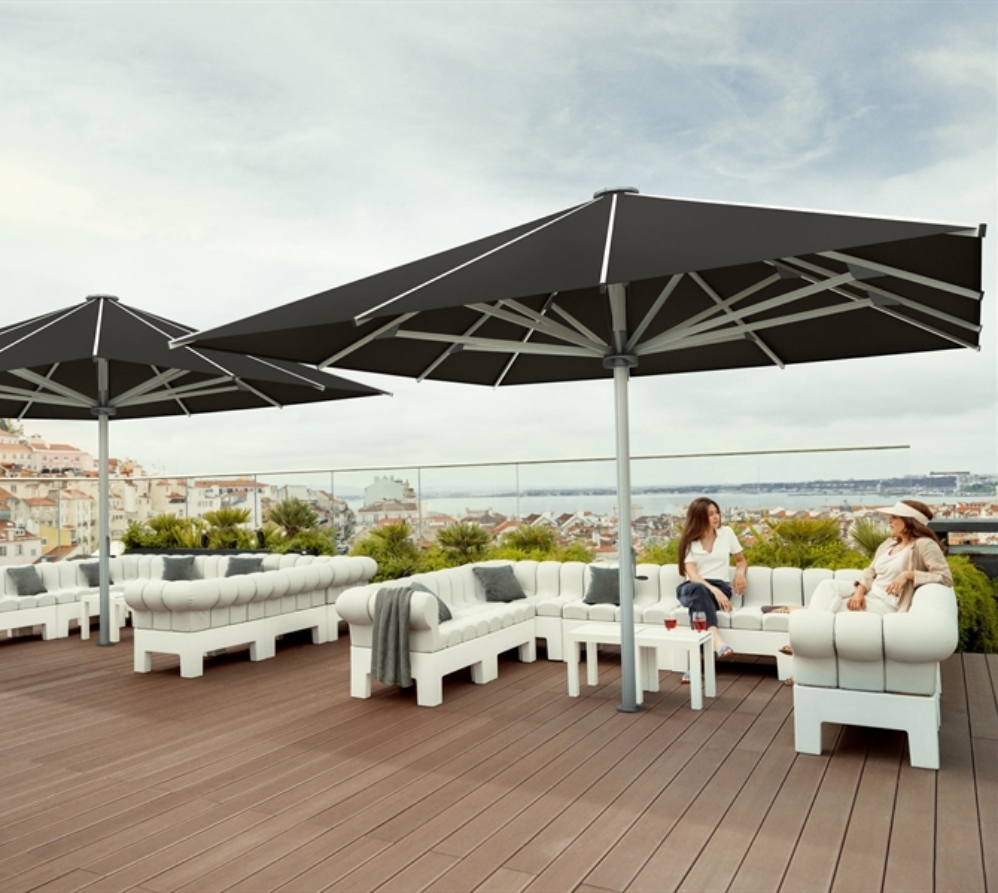 2 large black umbrellas covering a patio with 2 ladies sitting underneath one chatting