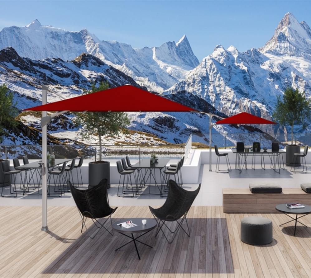 A modern style patio overlooking snowy mountains with 2 red umbrellas