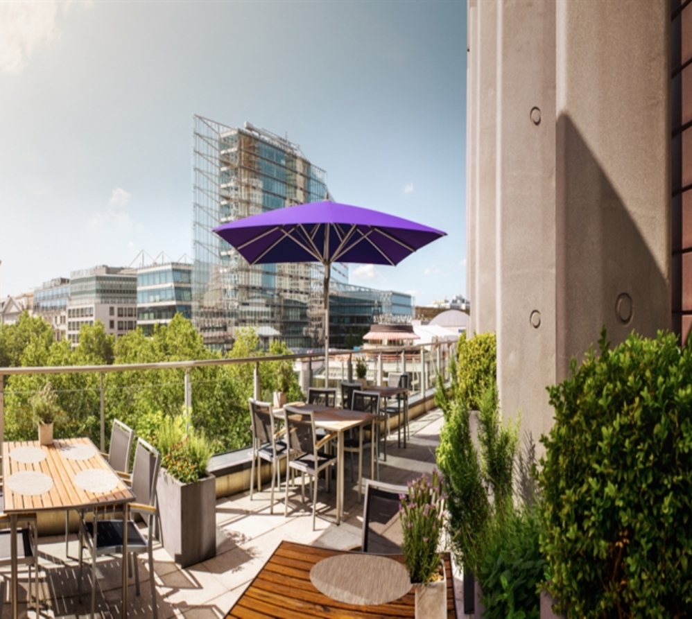 A single purple coloured umbrella on an elevated patio in a restaurant setting A single purple coloured umbrella on an elevated patio in a restaurant setting
