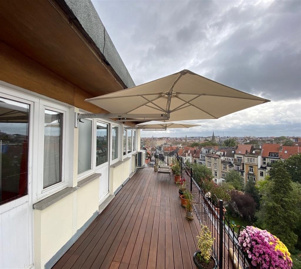 Prostor P3 wall-mounted umbrella with an extended telescopic arm over apartment patio.