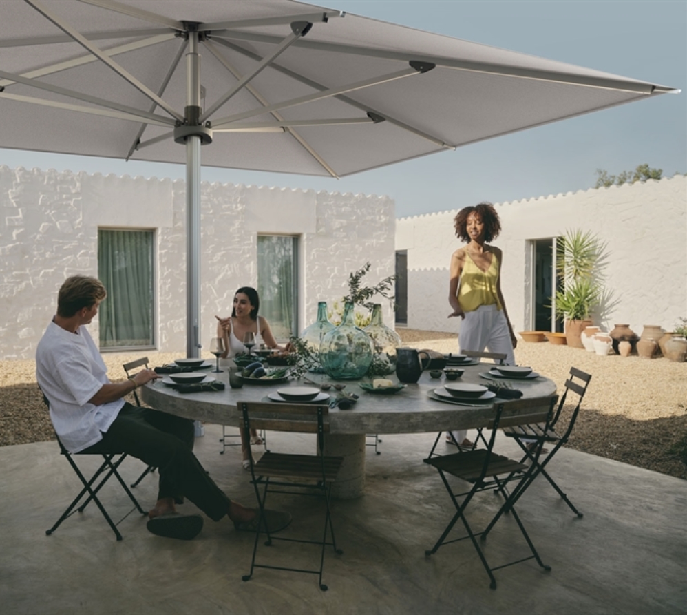 3 friends chatting and dining under a large white umbrella