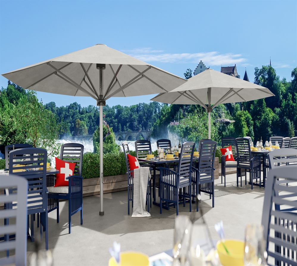 2 large white umbrellas on a restaurant patio overlooking a sea of large trees