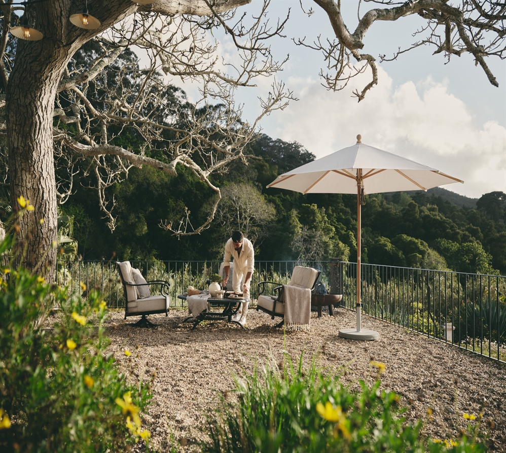 A classic style cream umbrella with wood fixations in a backyard overlooking many trees A classic style cream umbrella with wood fixations in a backyard overlooking many trees