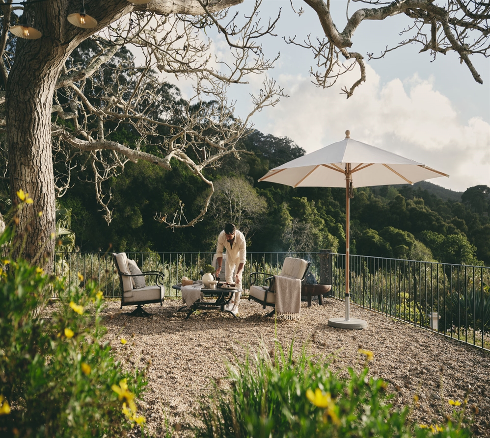 A classic style cream umbrella with wood fixations in a backyard overlooking many trees