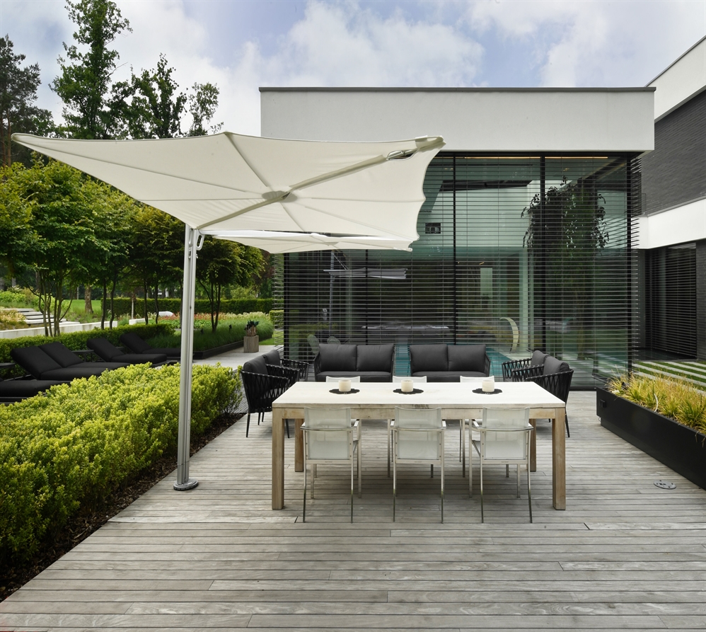 A Spectra Duo umbrella in white fabric covering a dining area of a residential patio space