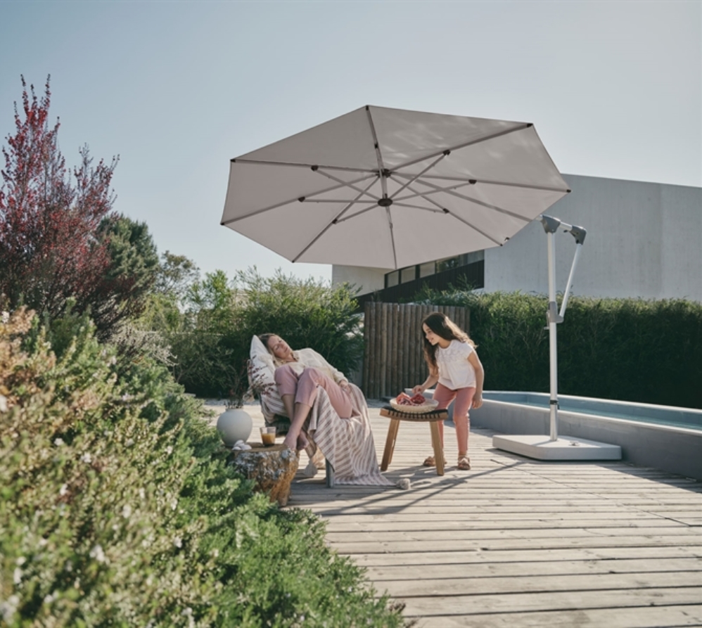 A white umbrella with flexible usability shading a family poolside in their backyard A white umbrella with flexible usability shading a family poolside in their backyard