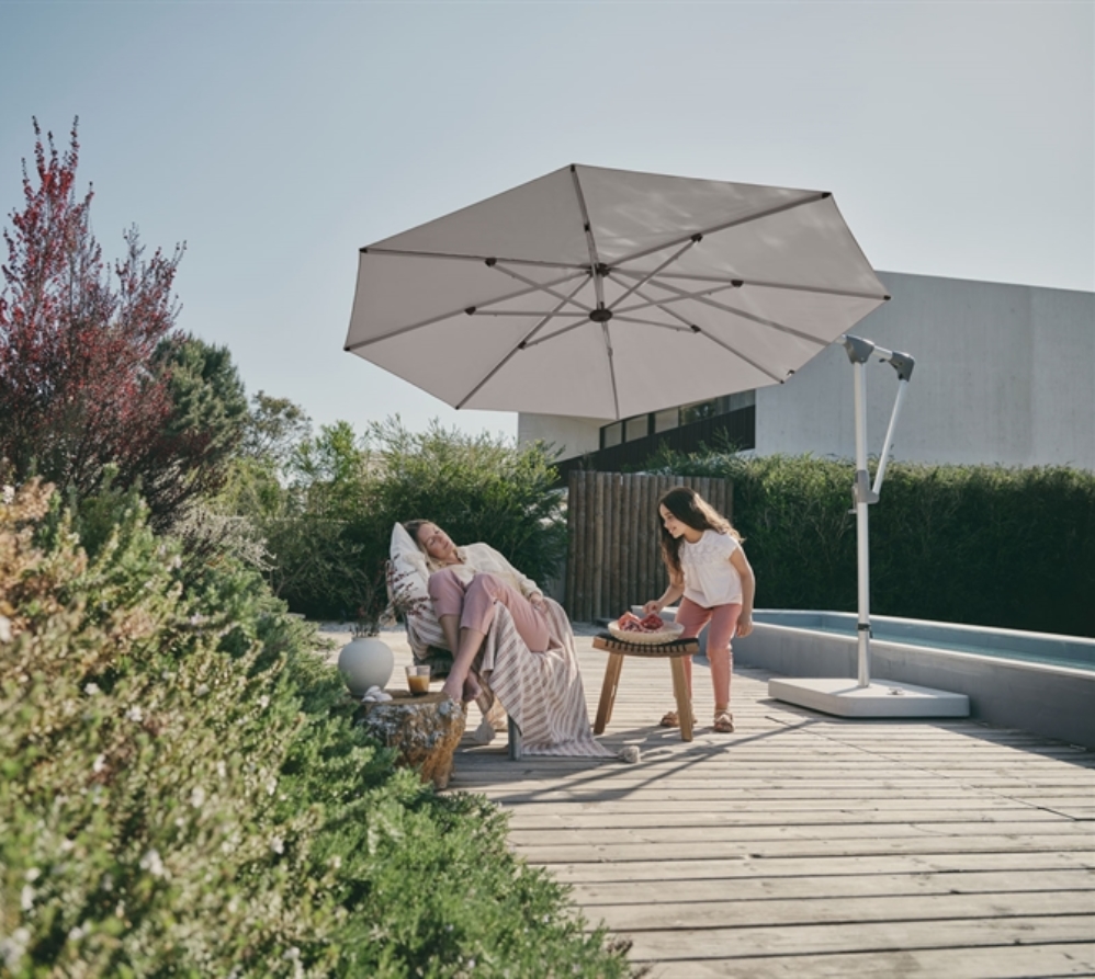 A white umbrella with flexible usability shading a family poolside in their backyard