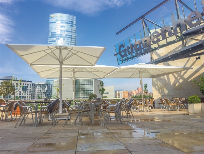 white umbrellas in the daytime covering an outdoor public patio area with seating underneath