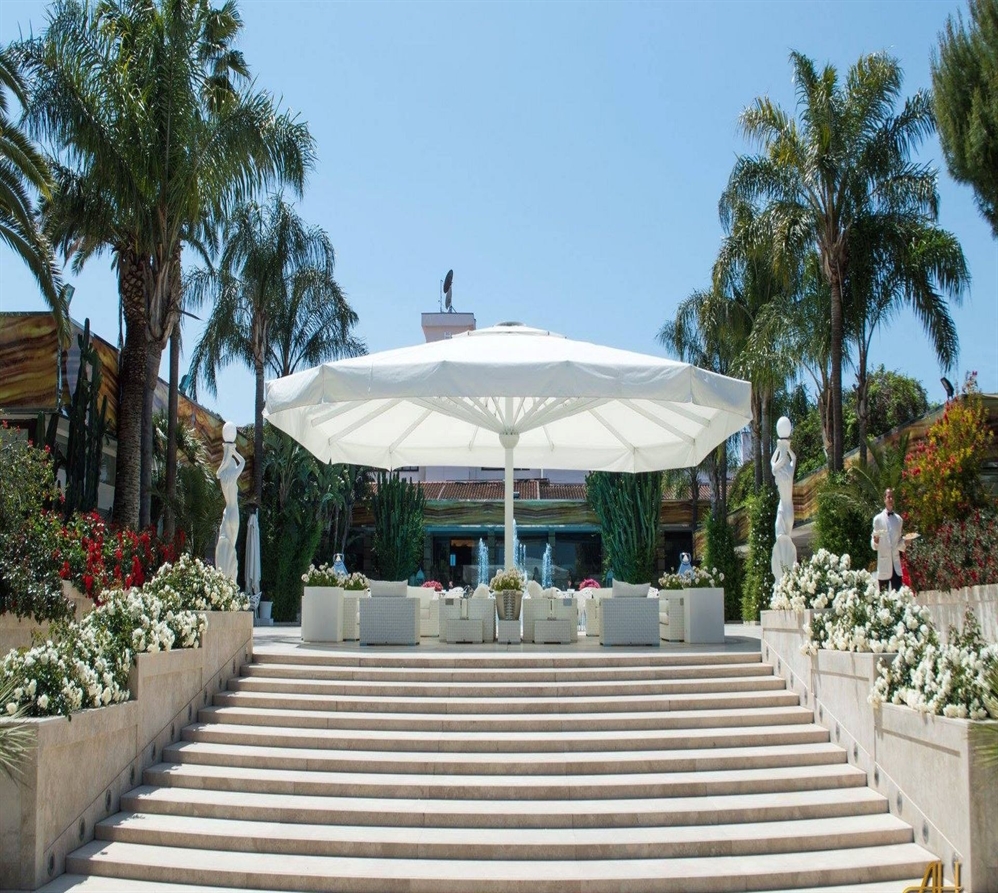 giant white patio umbrella covering a large outdoor public space with white chairs and tables below