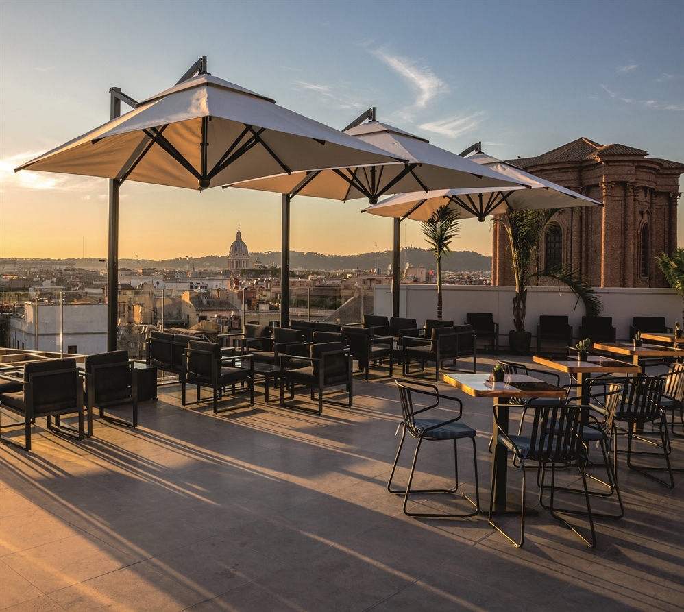 3 cream outdoor patio umbrellas next to each other covering an outdoor patio during sunset