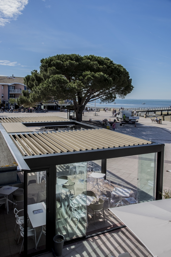 wooden style aluminum louvres integrated in an awning system with glass side panels at a restaurant