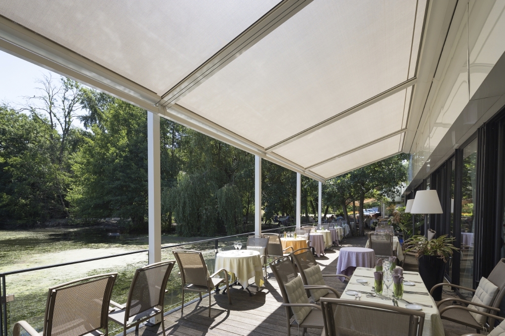 Restaurant patio with retractable PVC pergola in closed position Restaurant patio with retractable PVC pergola in closed position