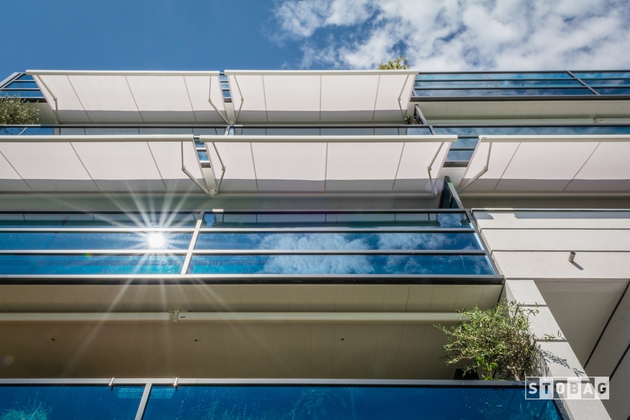 White arm bracket awning open and shading several apartment patios