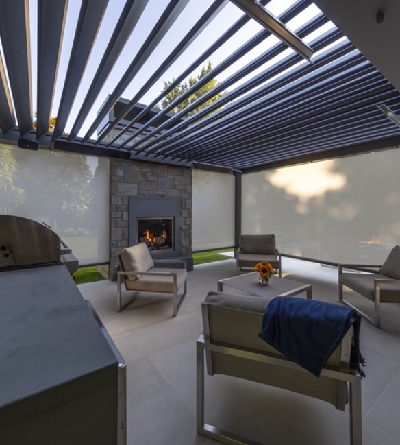 silver bioclimatic pergola with louvres above enclosed with grey motorized screens