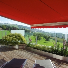 Red awning extended over an outdoor home patio looking out onto the landscape