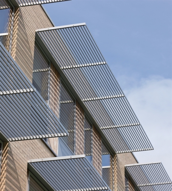 Horizontal brise-soleil Sunclips above the windows of a brick building