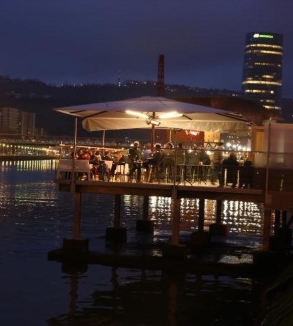 restaurant patio at night time with integrated lighting and people dining underneath