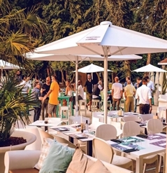 a series of white patio umbrellas placed across a large outdoor space hosting an event