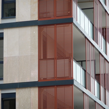 red aluminum sliding shutter panels installed on the balconies of apartments on a building