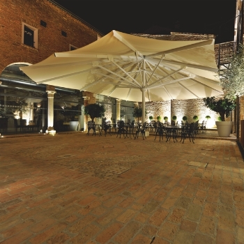 Cream Golia parasol open and covering outdoor restaurant patio at night
