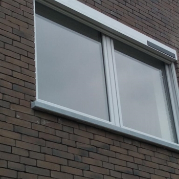 grey solar powered motorized screen installed on a brick style home