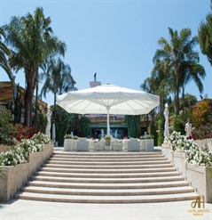 Extra large spanning Golia parasol shown extended over seating area of hotel
