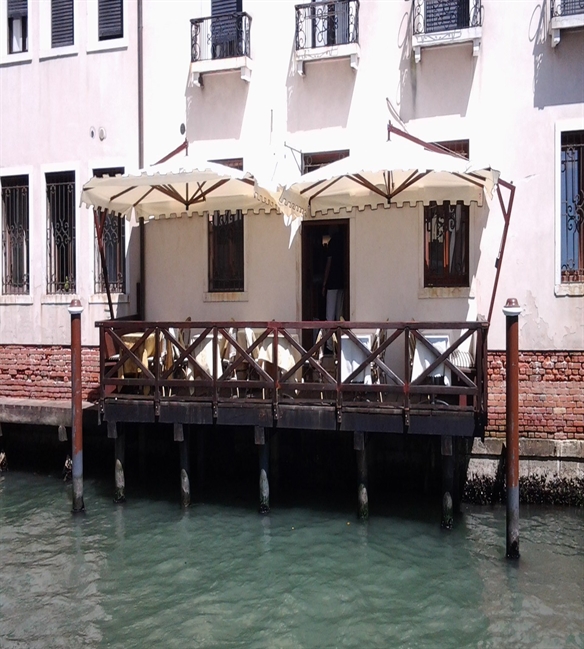 Cream side arm parasol over a restaurant patio above the canal