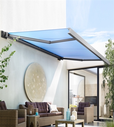 a retractable fabric blue awning attached to the facade of a white home with modern patio decor