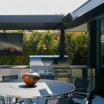 black freestanding pergola with an electric heater installed on it's frame covering a patio area