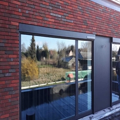 black coloured solar powered motorized screen installed on a home with the screen retracted