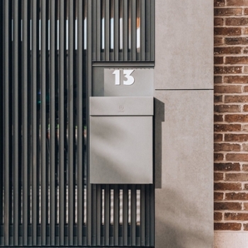 small aluminum black mailbox attached to the aluminum entry gate of an apartment