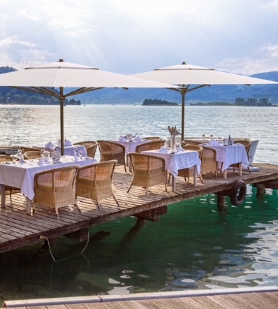 Two centre pole white parasols shading an outdoor dining area long the ocean peer