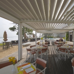 white louvred pergola covering the patio of a beachside restaurant in the daytime