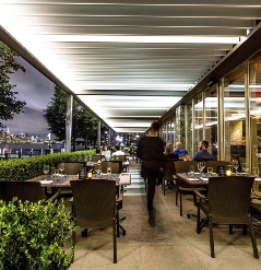 restaurant patio at night with customers underneath with louvred pergola above with led lighting