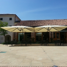 Two cream parasols open and shading restaurant outdoor dining area
